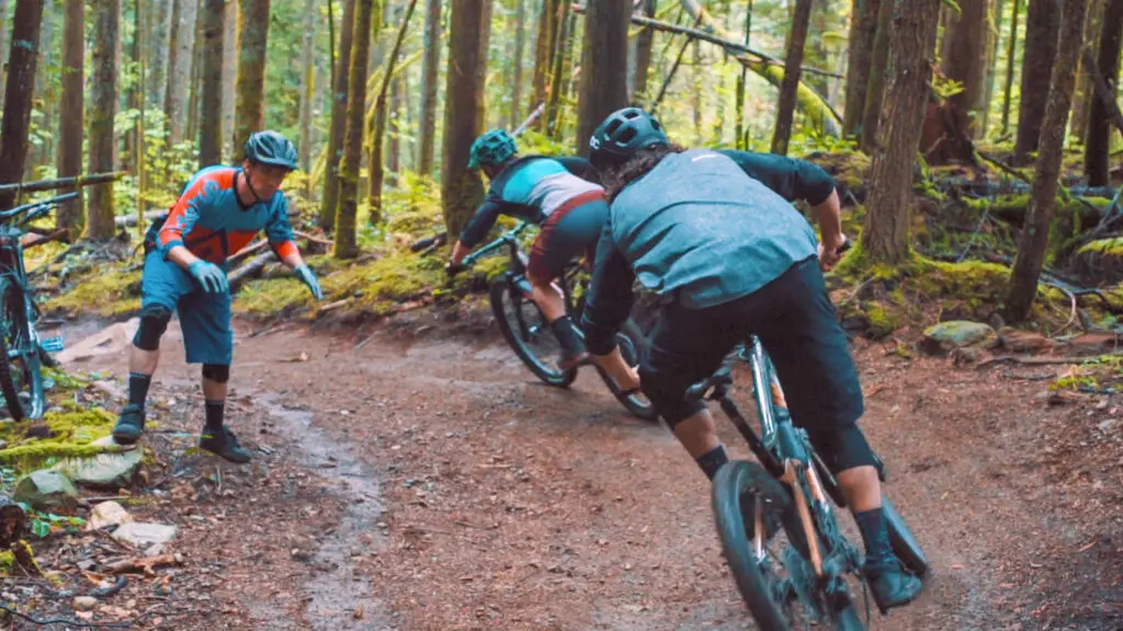 A group of adventure-seeking mountain bikers bravely ride down a thrilling trail in the picturesque woods of Squamish.
