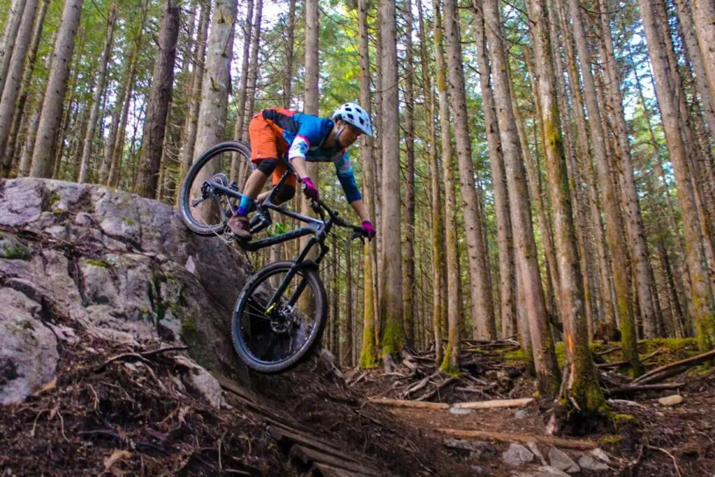 A person enjoying a thrilling mountain biking adventure through the lush woods.