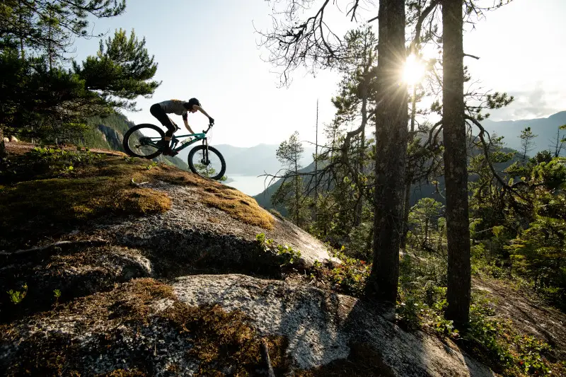 Mountain biker traversing a rocky trail at sunset.